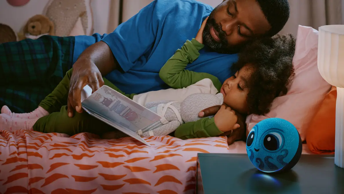 Parent reading a book to a child in bed with an Amazon Kids Echo Dot on the nightstand