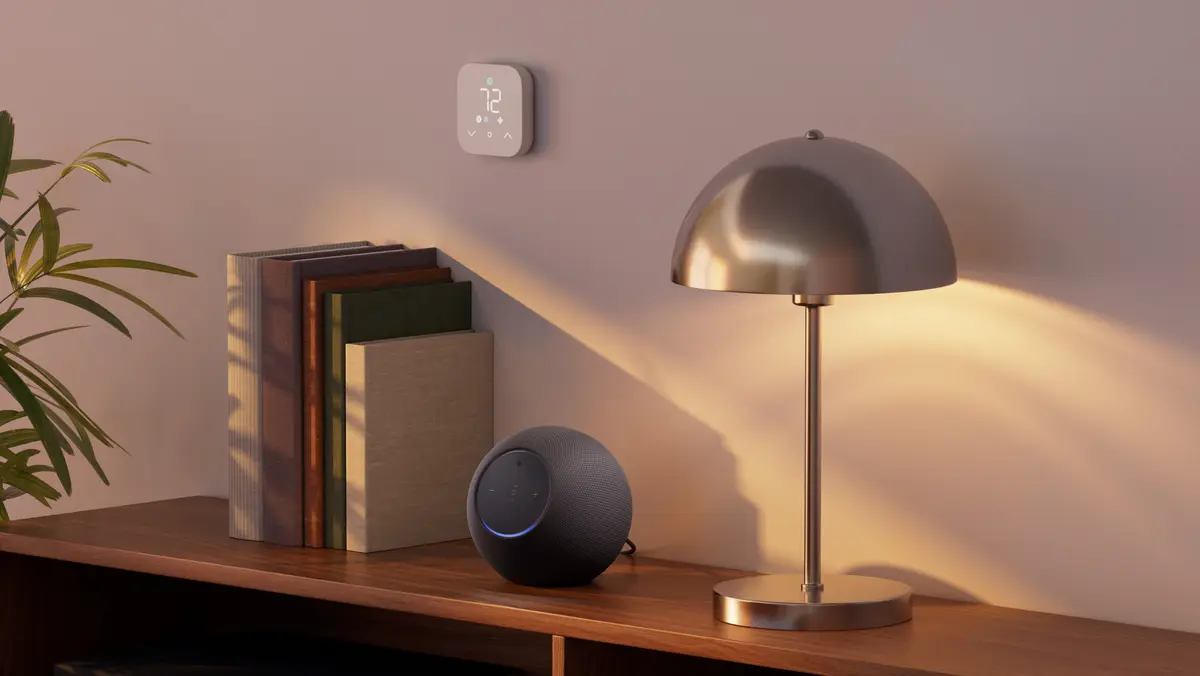 Echo Studio speaker on a shelf next to books and a lamp