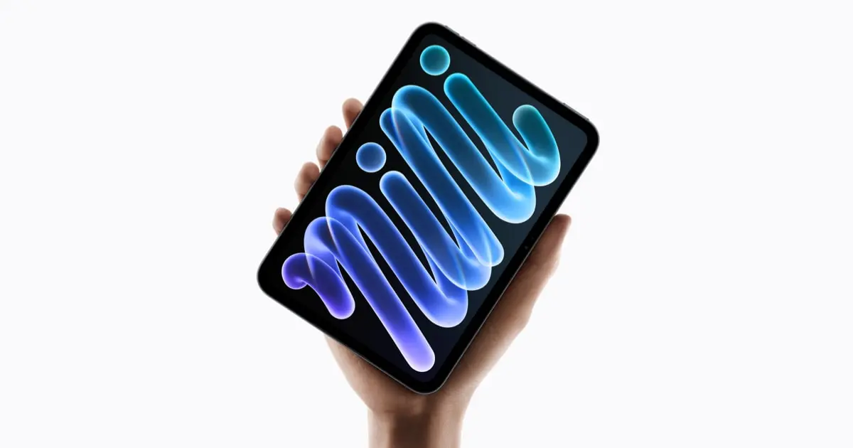 A hand holding the new iPad mini showing a colourful wallpaper