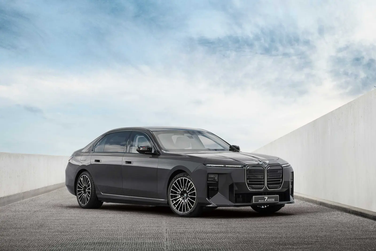 Dark grey BMW 7 Series sedan parked between white concrete walls