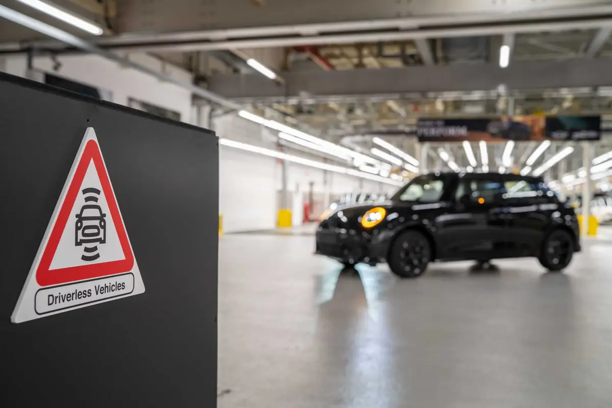 Driverless Vehicles warning sign beside a MINI moving through MINI Plant Oxford