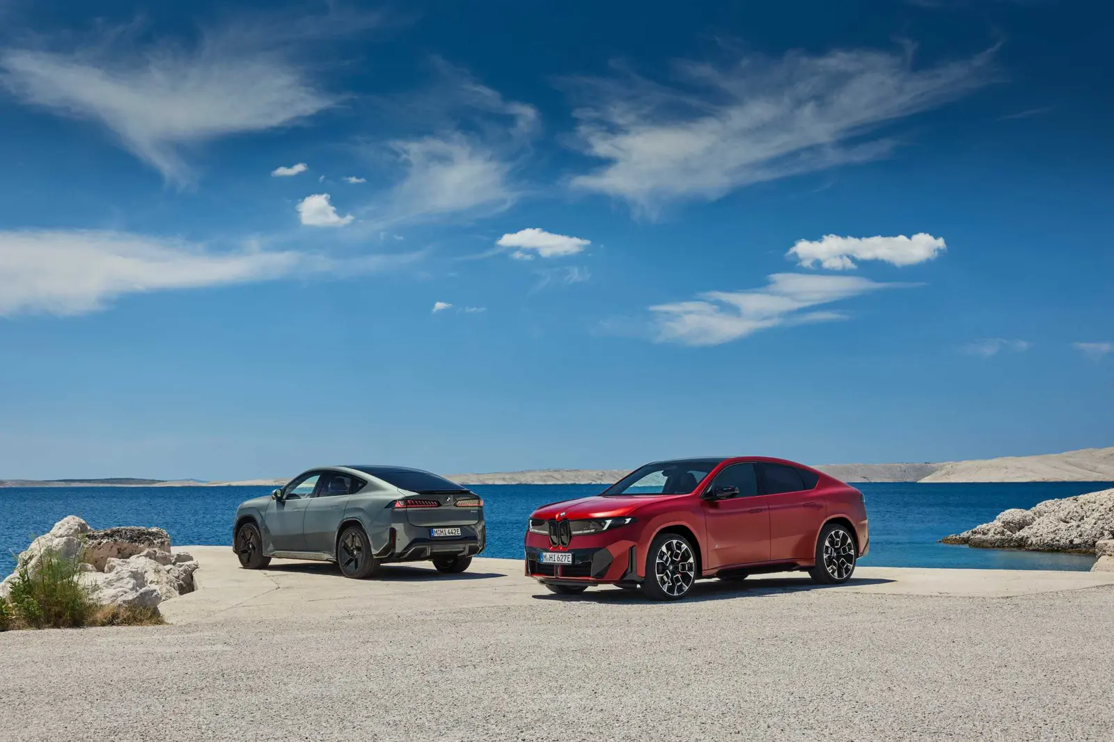 Two BMW iX4 SUV coupes parked by the sea