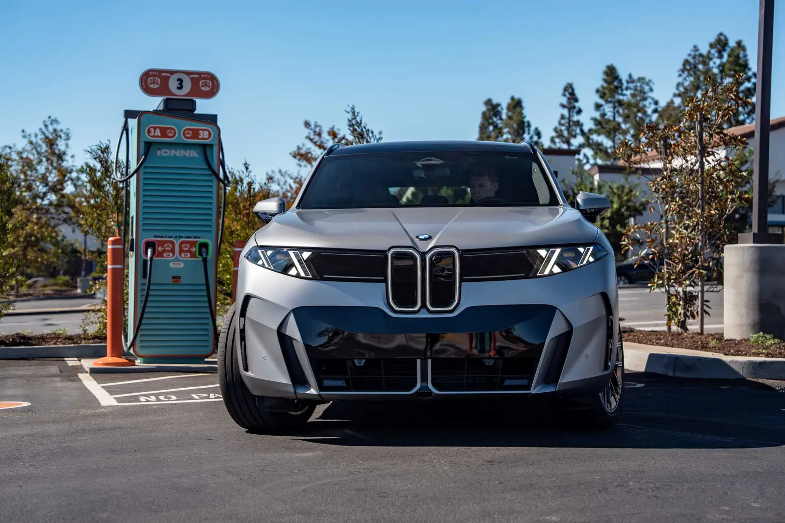 Silver BMW iX5 parked in front of an IONNA charging station