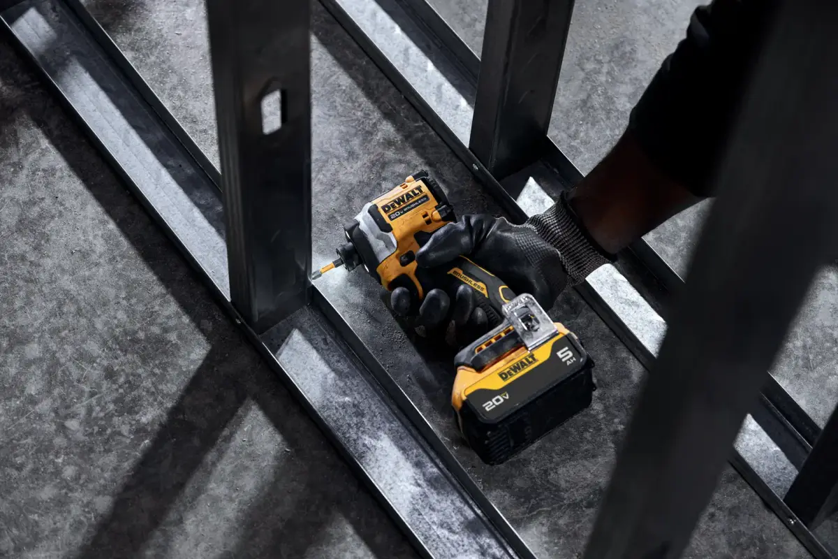 ਇੱਕ ਕਾਰੀਗਰ DEWALT ATOMIC ਨਾਲ ਧਾਤ ਦੇ ਫ਼ਰੇਮ ਵਿੱਚ ਪੇਚ ਲਾ ਰਿਹਾ ਹੈ