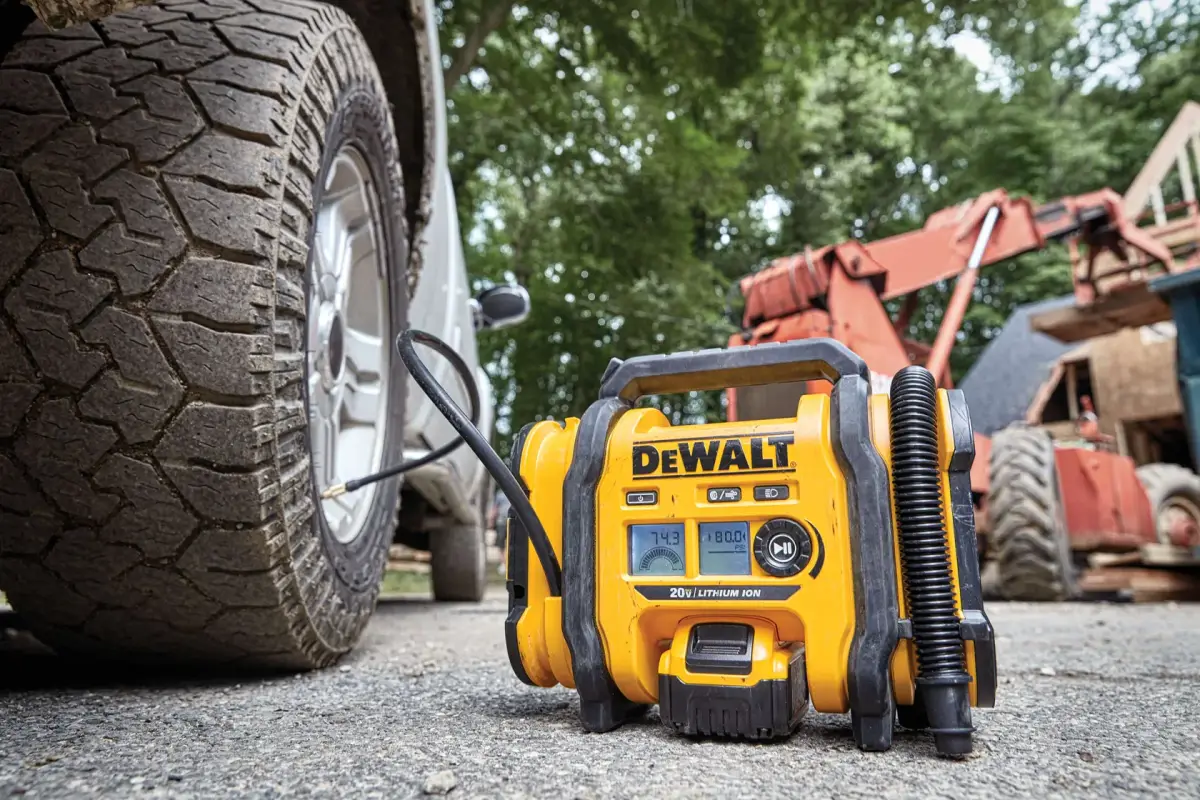 DEWALT DCC020IB inflator on the ground beside a truck tire at a jobsite