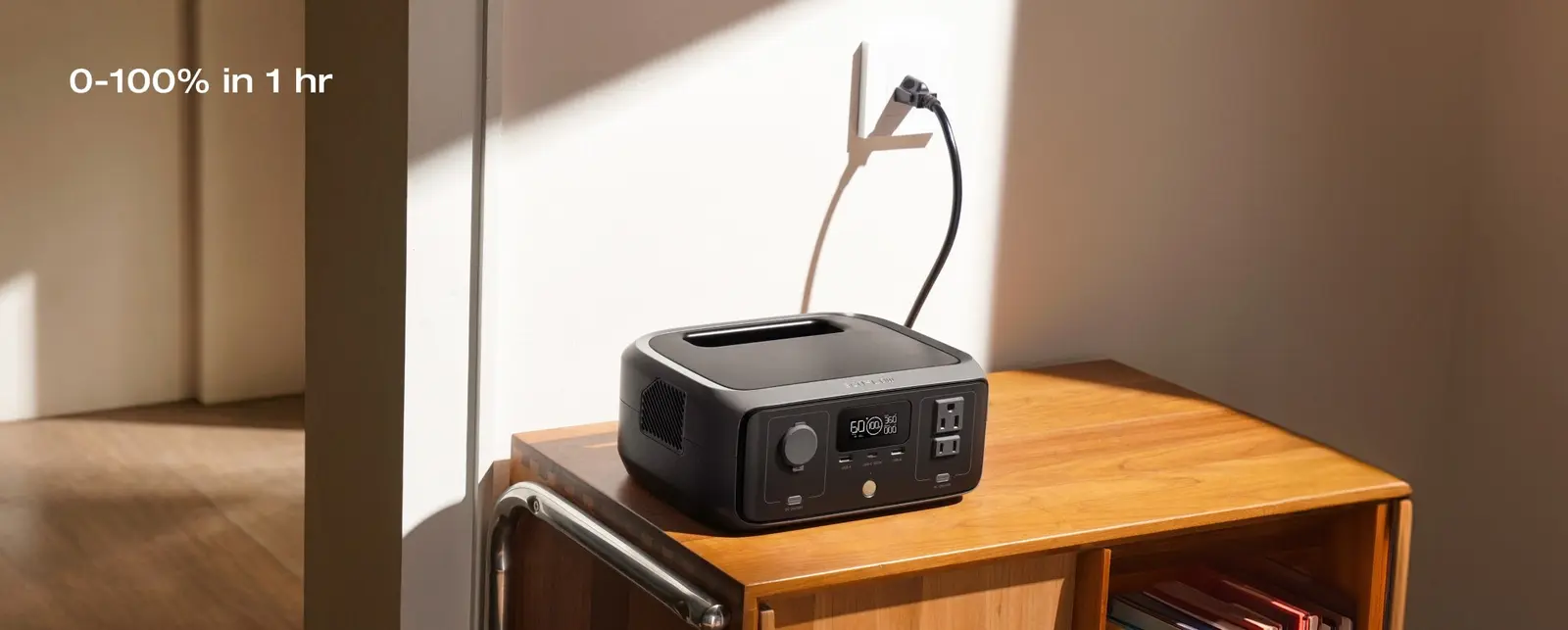 EcoFlow RIVER 3 portable power station plugged into a wall outlet on a wooden shelf