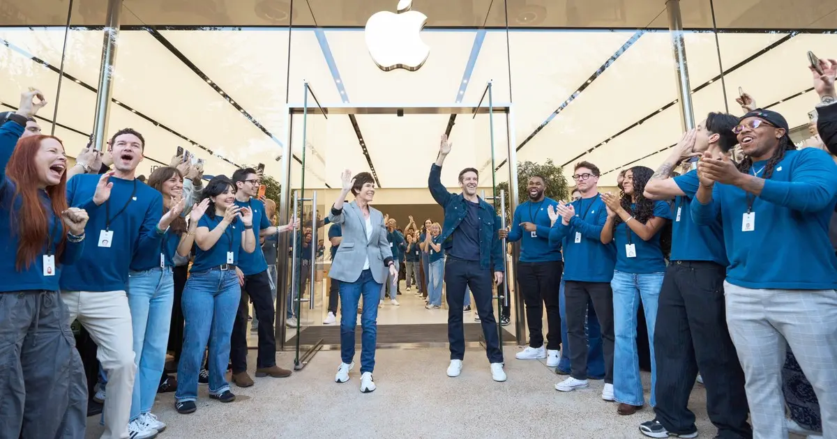 Apple team members cheer customers at the entrance of an Apple Store on iPhone Duo launch day