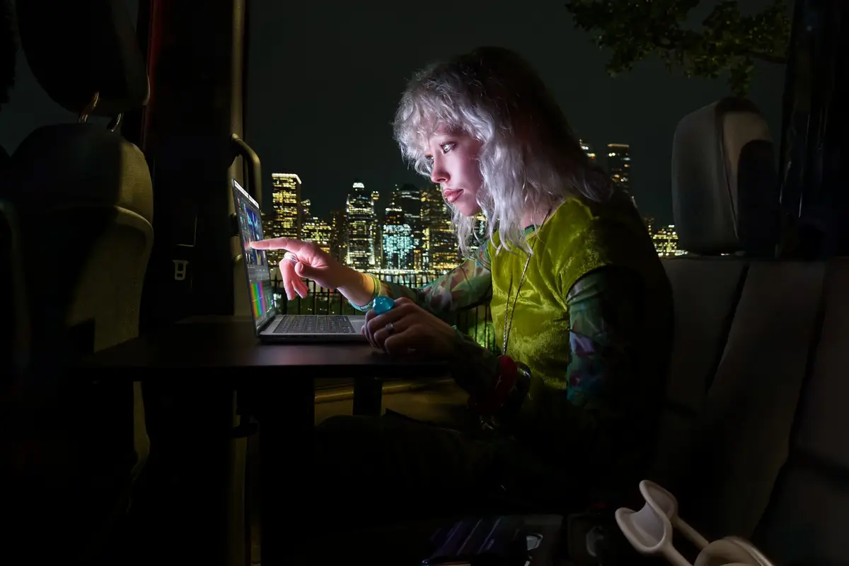 A person using the touch screen of the new MacBook Pro while travelling at night