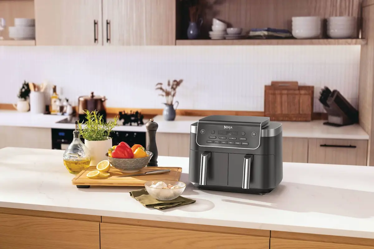 Ninja DualZone air fryer on a kitchen counter next to fresh vegetables and oil