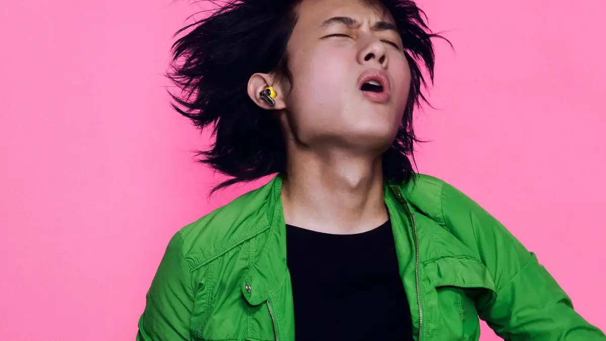 Person wearing a Nothing Ear (3a) earbud against a pink background