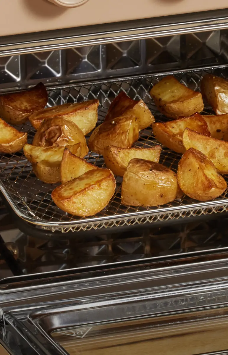 Golden potato wedges roasting on a wire rack inside the Wonder Oven