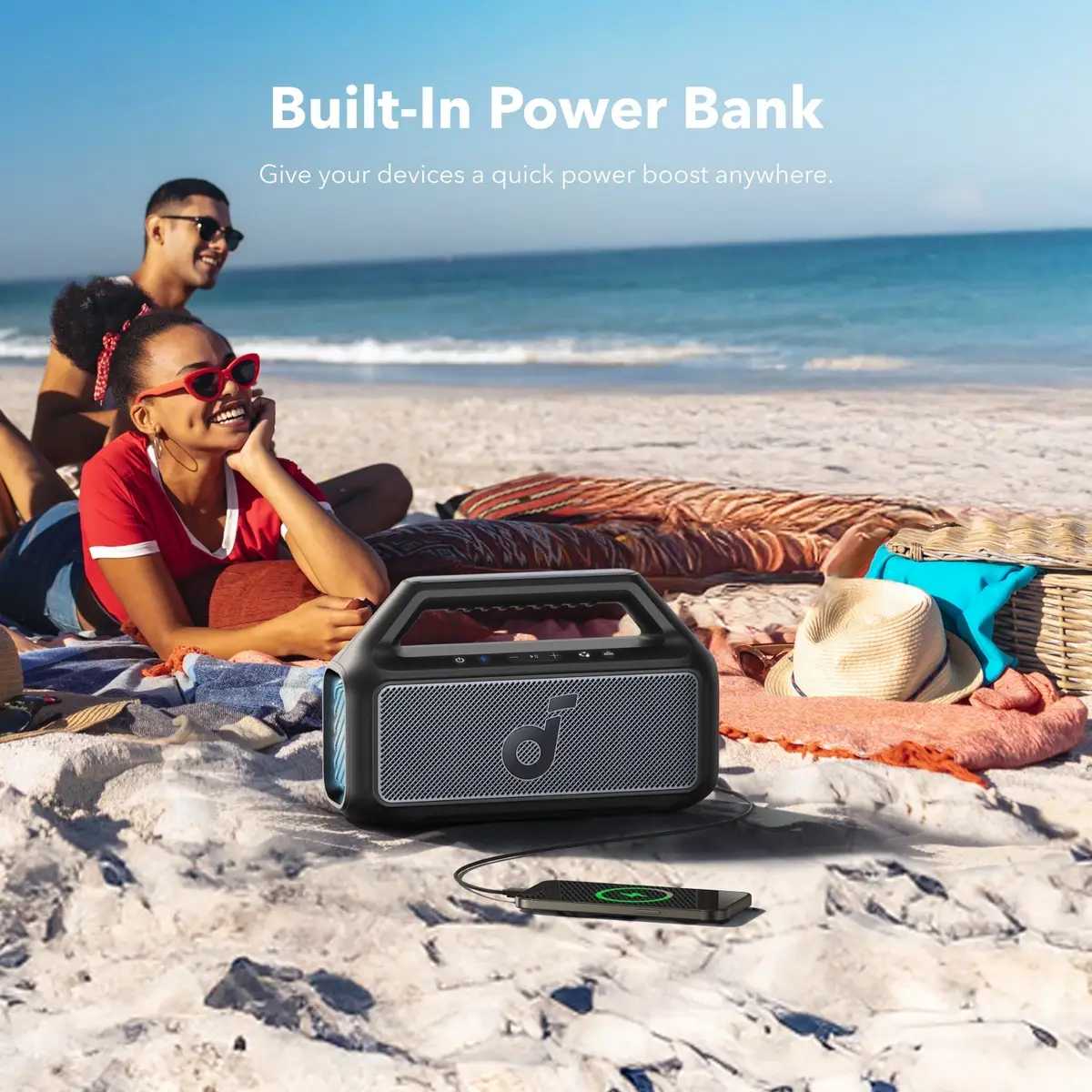 Friends relaxing on a beach with the Boom 2 charging a phone