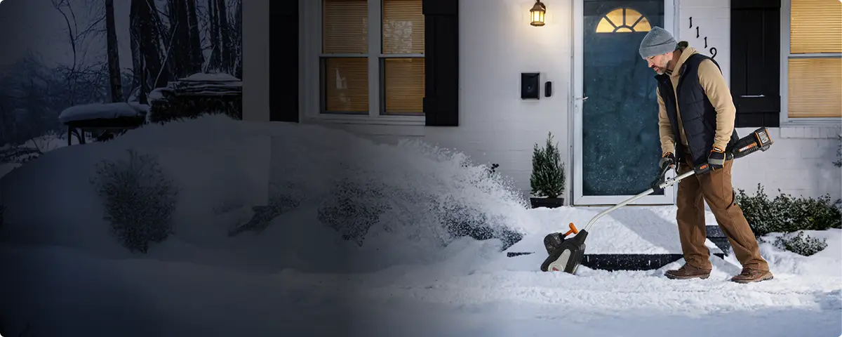 Man throwing snow off a front walk with the WORX shovel at night