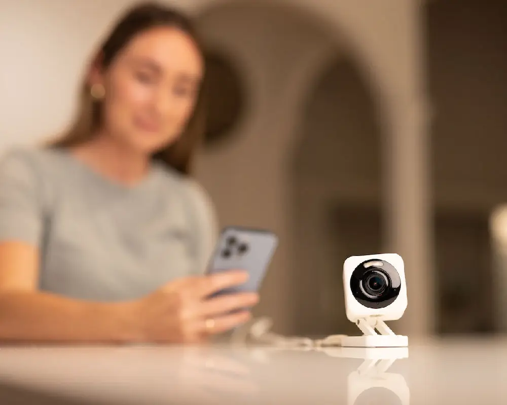 A person checking the Wyze app on a phone with the camera on a table