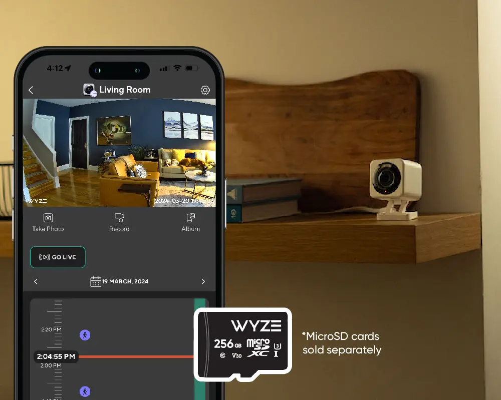 Wyze app timeline on a phone beside a camera on a shelf and a microSD card
